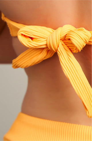 Close-up detail of the horizontal ribbed orange fabric tied in a large bow on the back of the bikini top for adjustable closure