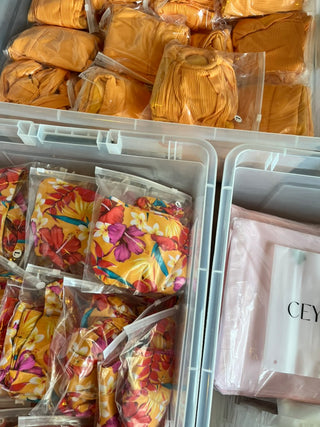 Container with yellow hair ties and floral-patterned hair ties on a gray surface.